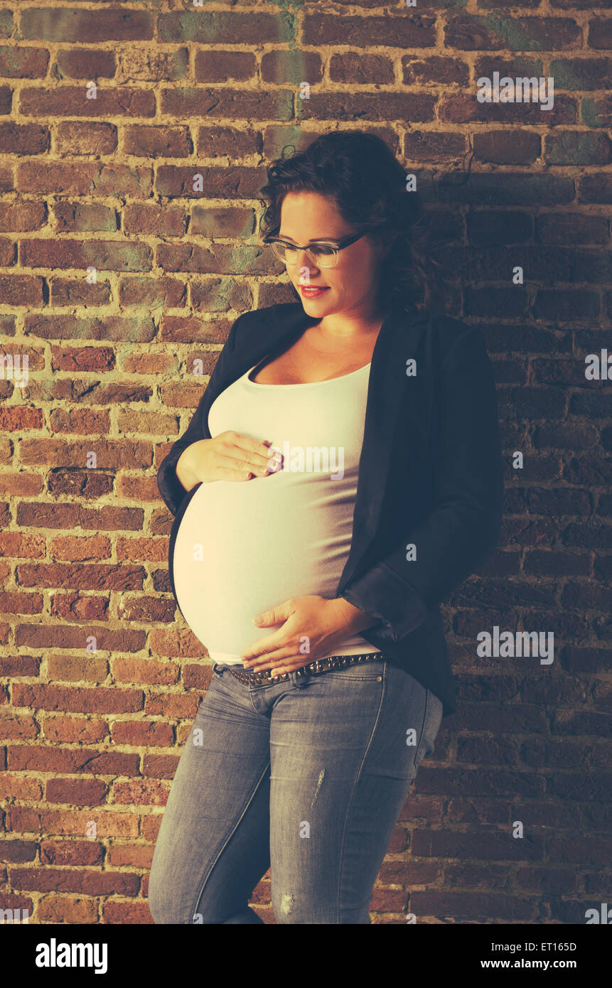 Femme enceinte devant un mur en situation urbex Banque D'Images
