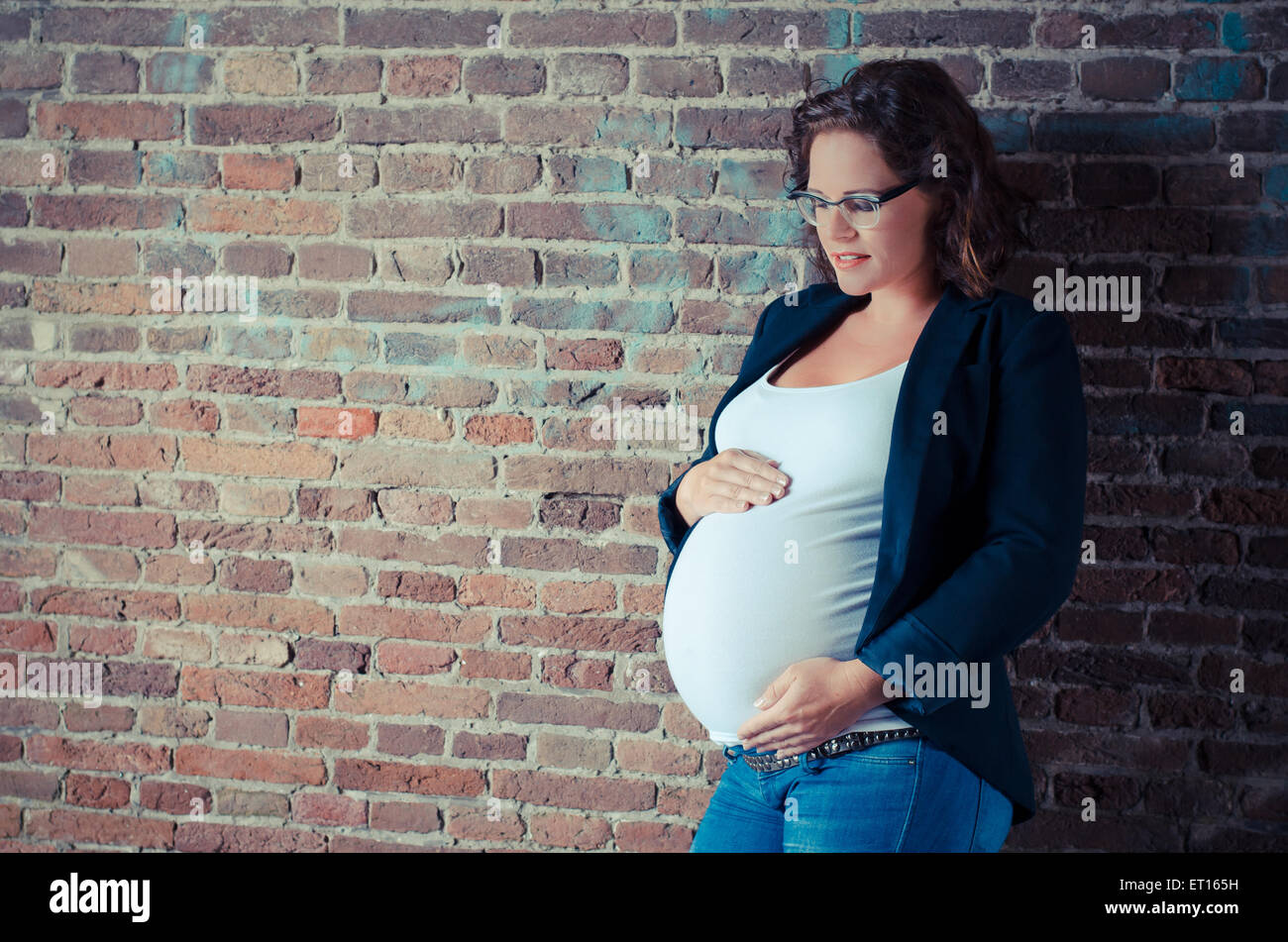 Femme enceinte devant un mur en situation urbex Banque D'Images