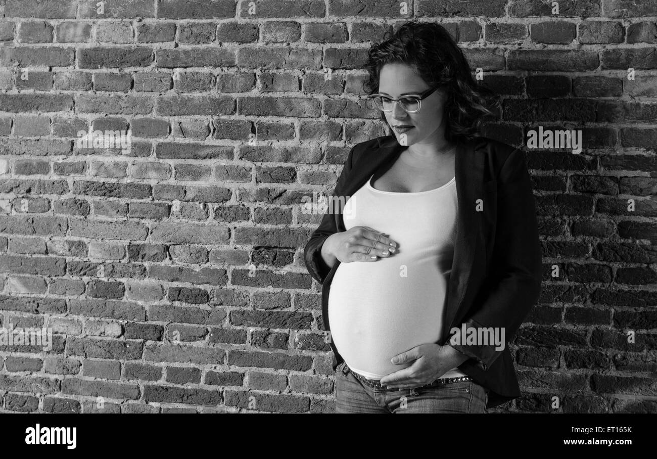 Femme enceinte devant un mur en situation urbex Banque D'Images