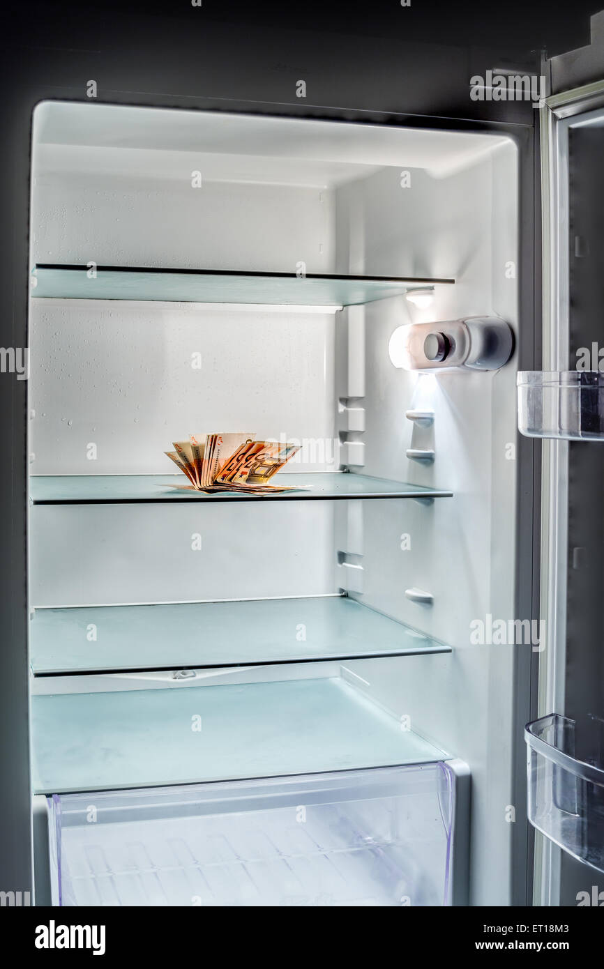 De l'argent frais dans le réfrigérateur : une poignée de billets de 50 euros éclairé par la lumière froide d'un réfrigérateur vide Banque D'Images