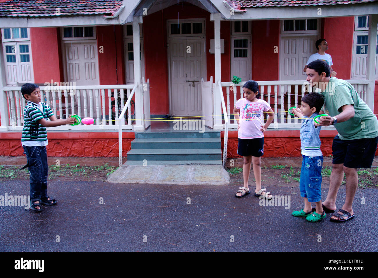 Père de famille et enfants jouant nouveau jeu avec cordes et ball in front of house - M.# 364 smr - 179832 Banque D'Images