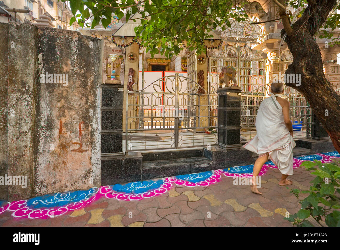 Jain Devotee marchant à côté de rangoli coloré décor de plancher à l'extérieur de Jain temple pour le festival, Bombay, Mumbai, Maharashtra, Inde,Asie, Asie, Indien Banque D'Images