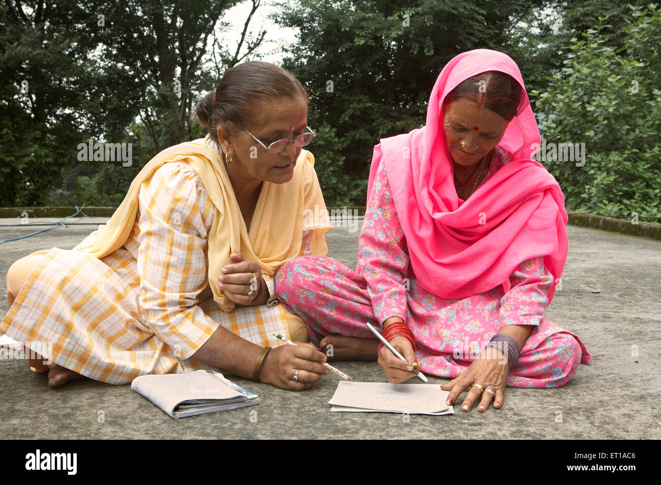 Femme volontaire enseignant à la vieille dame d'écrire le programme d'alphabétisation des adultes initiative socio-économique lancée par l'ONG Chinmaya Organisation Inde Asie Banque D'Images