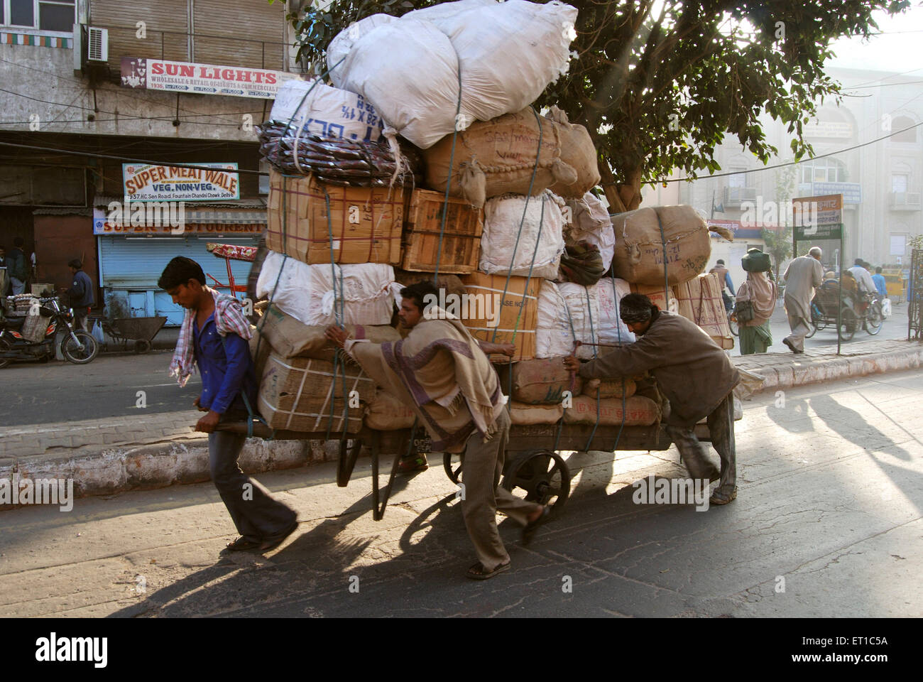 Les hommes tirent le chariot de poussée avec des bagages lourds dans la région de Chandni Chowk ; Delhi ; Inde Banque D'Images