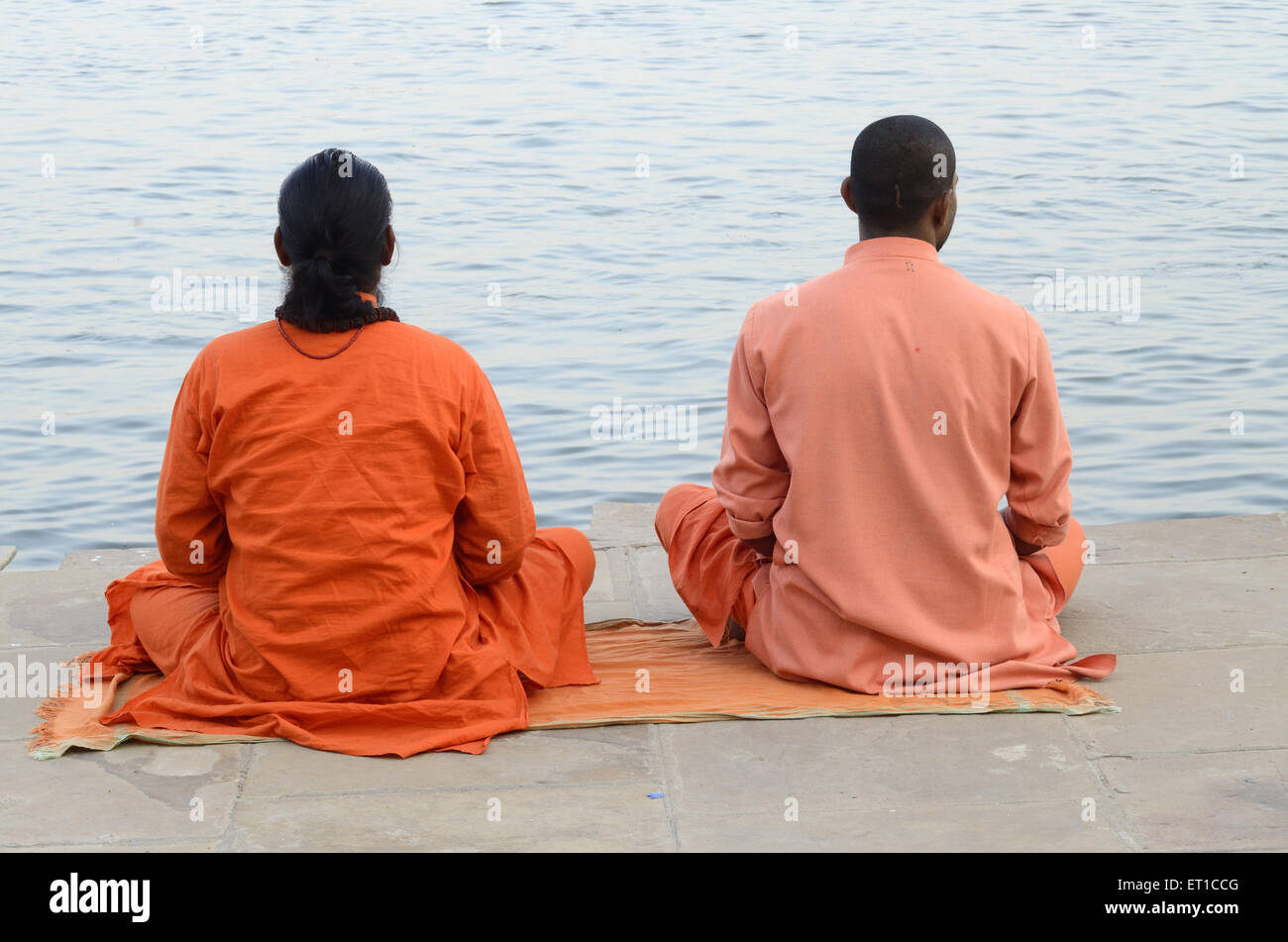 Prêtre la méditation assise dans la position sur la rivière Ganga ghat de Varanasi dans l'Uttar Pradesh en Inde Banque D'Images