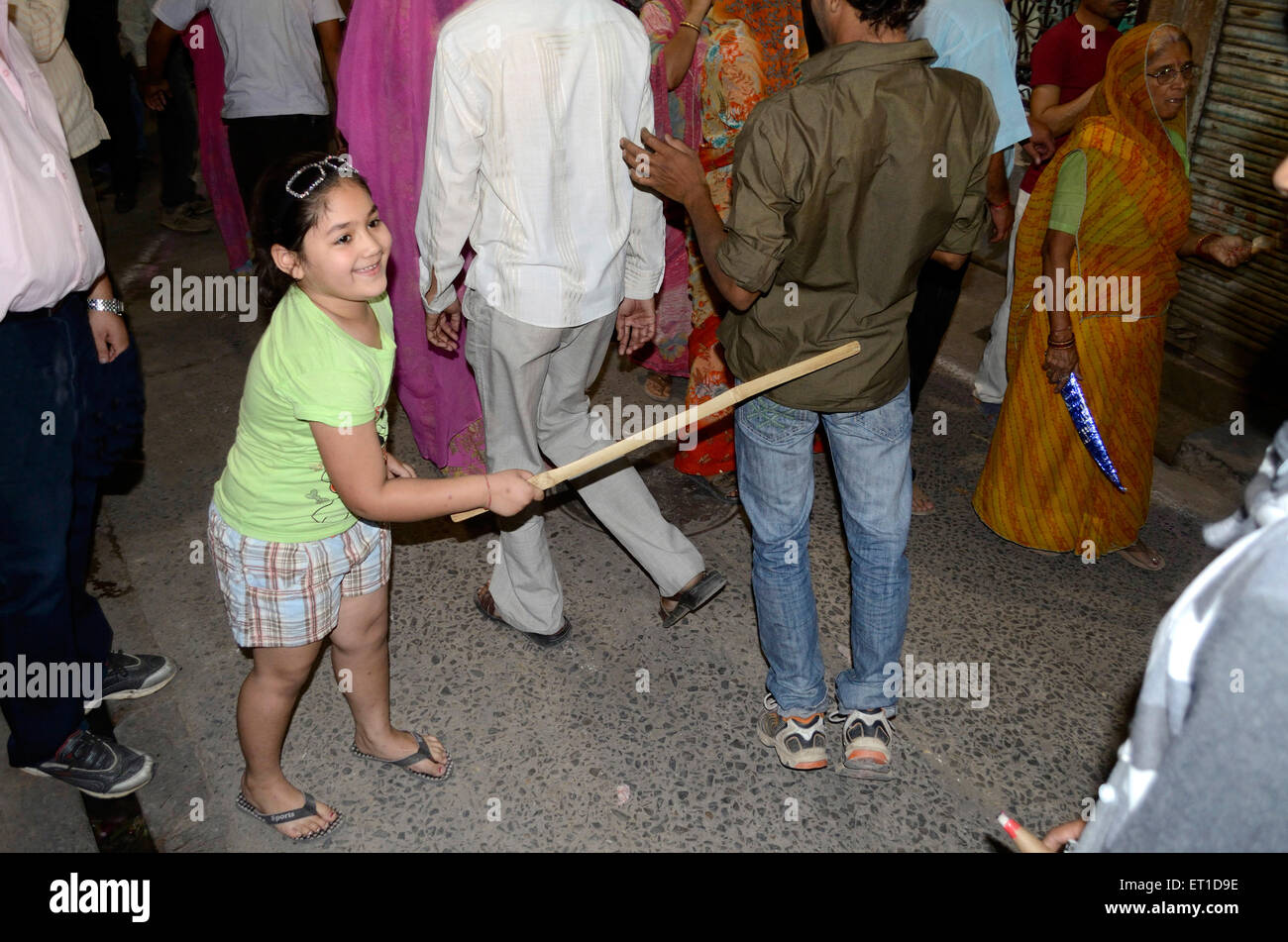 Une petite fille légèrement battre les garçons avec stick avec à l'occasion d'Dheenga Gavar Jodhpur Rajasthan Inde festival no mr Banque D'Images