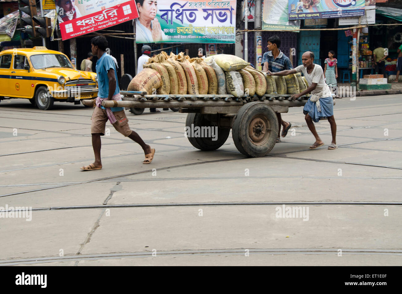 Hommes portant des bottes de ciment sur charrette Kolkata West Bengal India Asie Banque D'Images