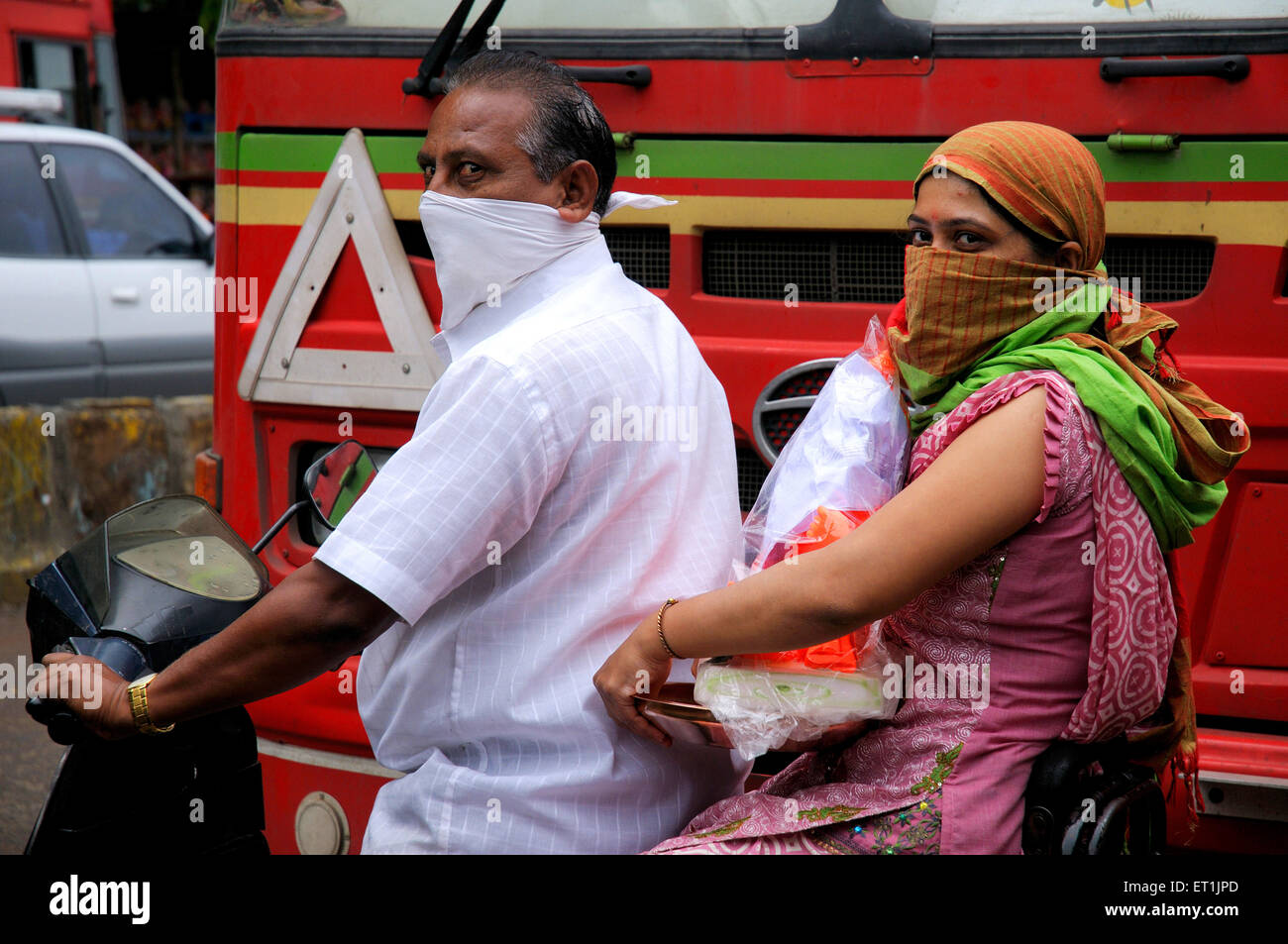 Couple portant des masques pour la sécurité et la précaution, portant Lord Ganesh sur scooter, Pune, Maharashtra, Inde Banque D'Images