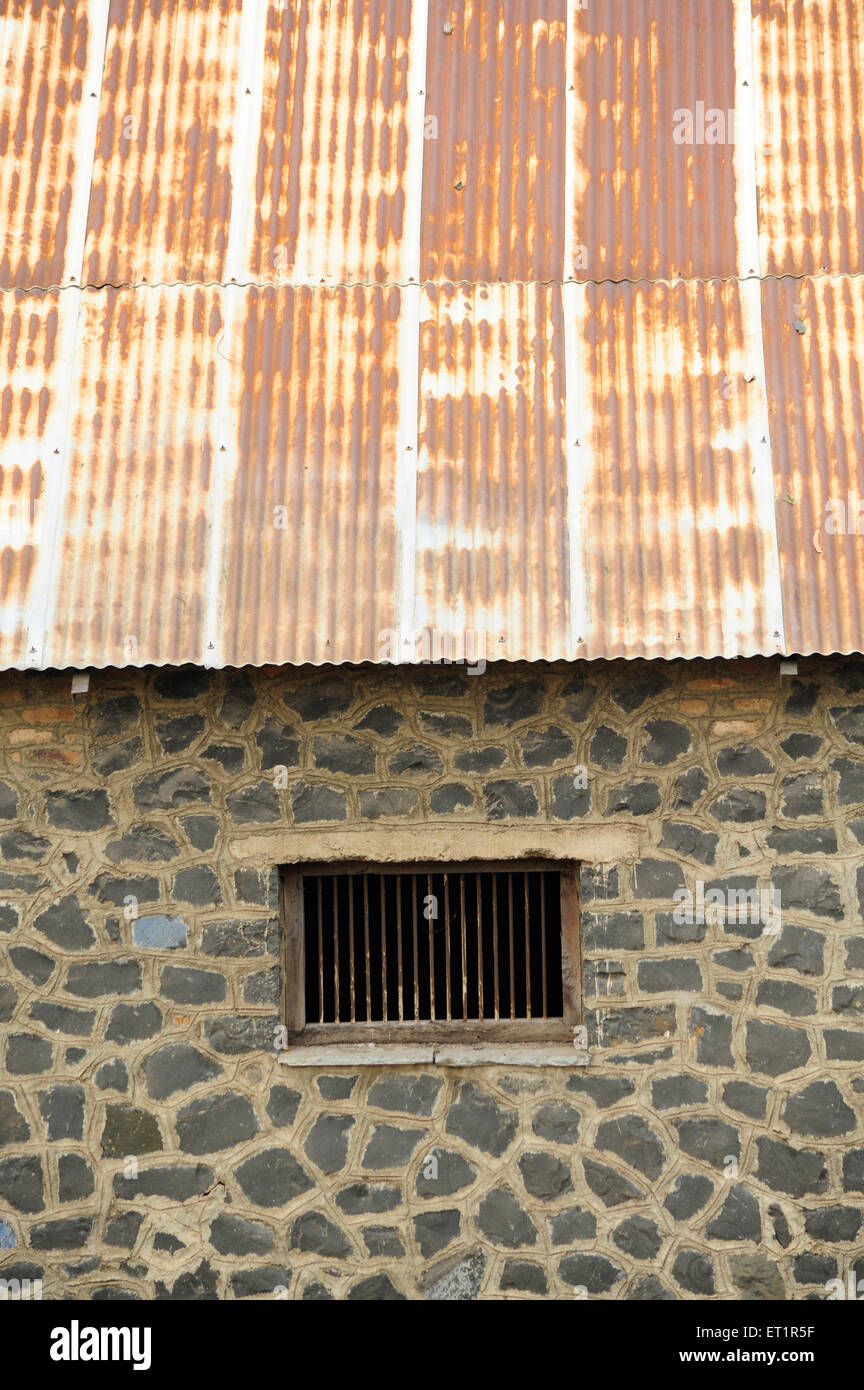 Mur en pierre avec fenêtre et toit en métal rouillé ; Akluj ; Solapur ; Maharashtra ; Inde Banque D'Images