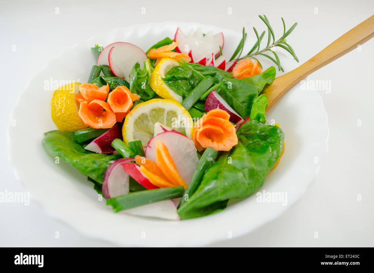 Salade fraîche contenant de la laitue, carottes, citron, romarin, oignons, radis, Banque D'Images