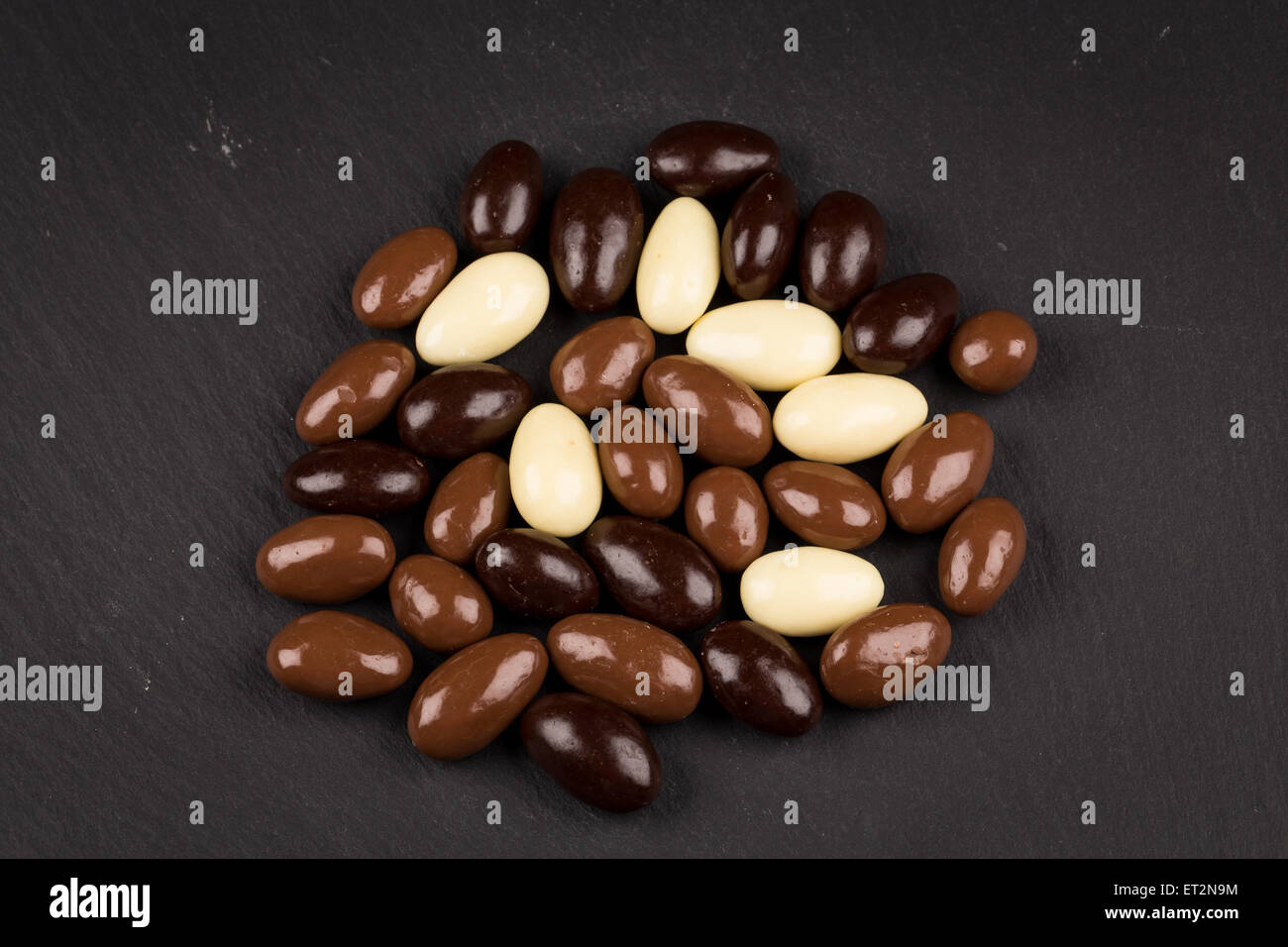 Les amandes en blanc, noir, chocolat au lait sur le conseil de pierre Banque D'Images