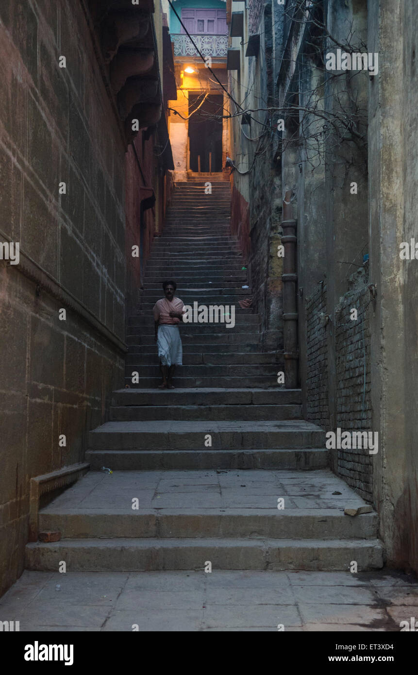 Un homme descend les marches vers la peur de ghats au bord du Gange à Varanasi Banque D'Images