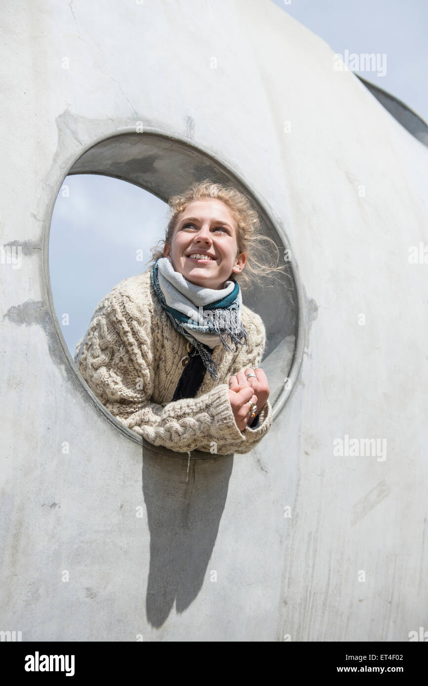 Jeune femme regardant à travers un trou rond à béton Bavière Munich Allemagne Banque D'Images