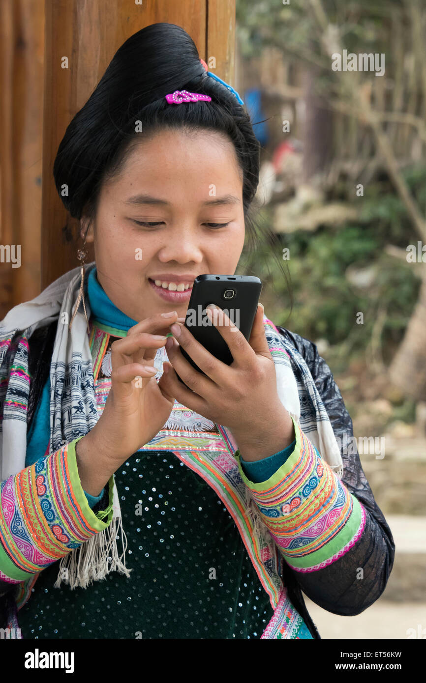 Miao Basha femme en tenue traditionnelle avec la technologie moderne, Basha Village des armes à feu, la province du Guizhou, Chine Banque D'Images