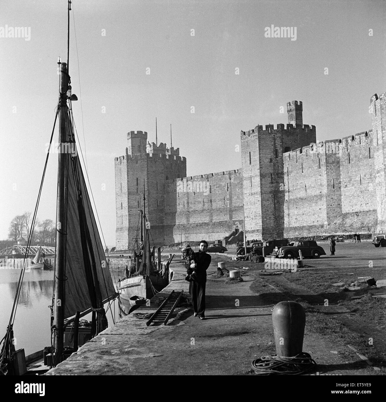 Un homme marchant passé Château de Caernarfon, Gwynedd. Vers 1952. Banque D'Images