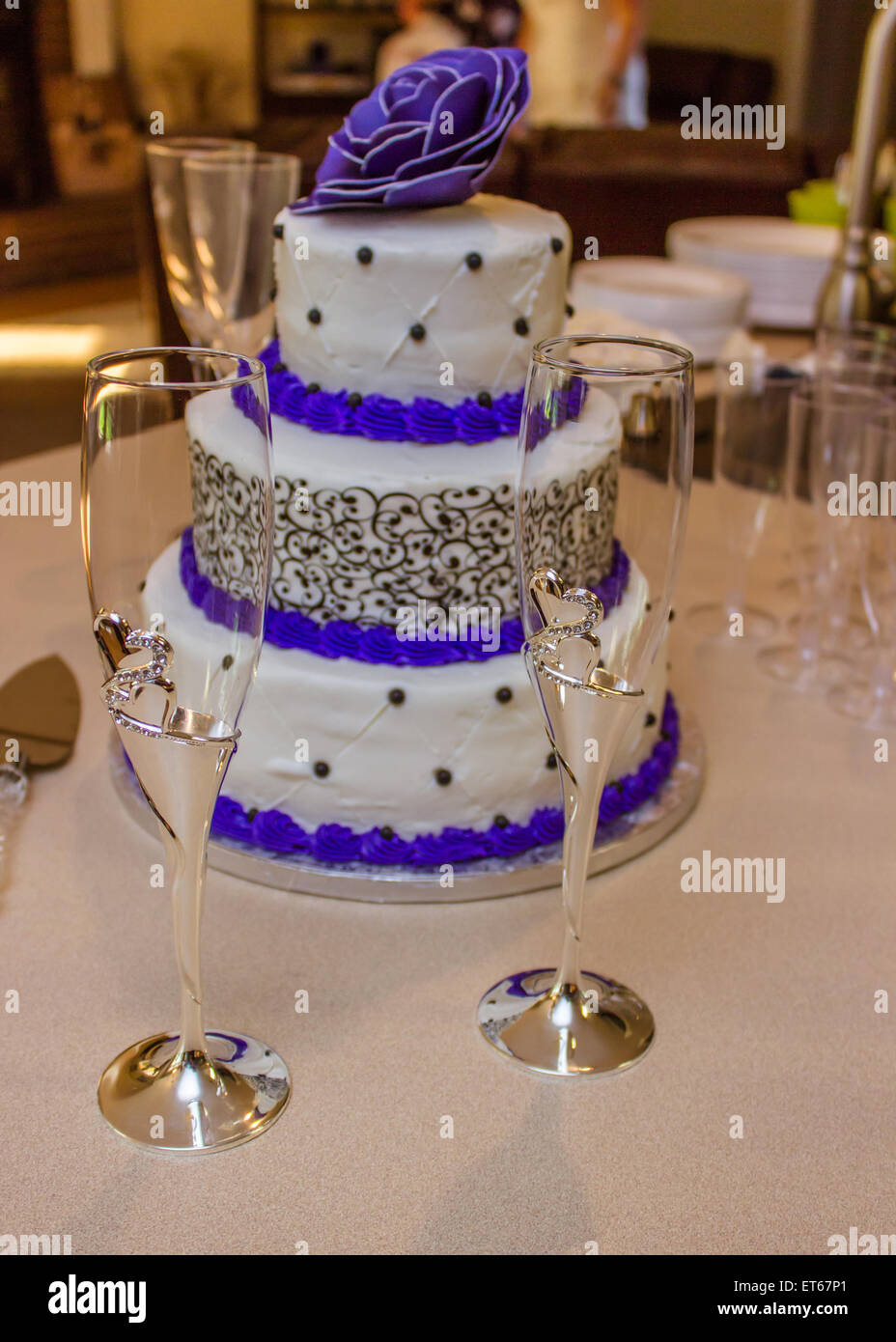 Gâteau de mariage avec de grandes fleurs pourpres et verres de champagne Banque D'Images