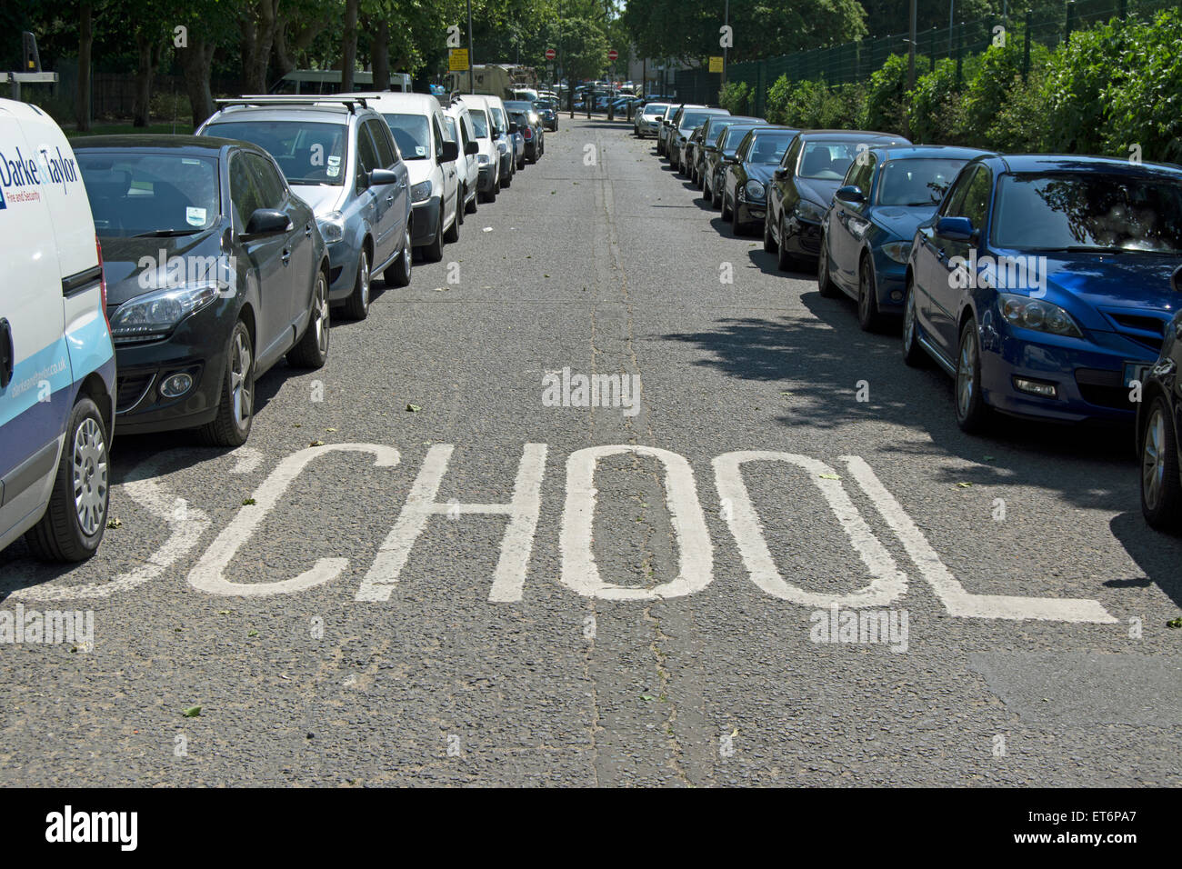 Signalisation pour l'école bordée par des pare-chocs à pare-chocs des voitures en stationnement Banque D'Images