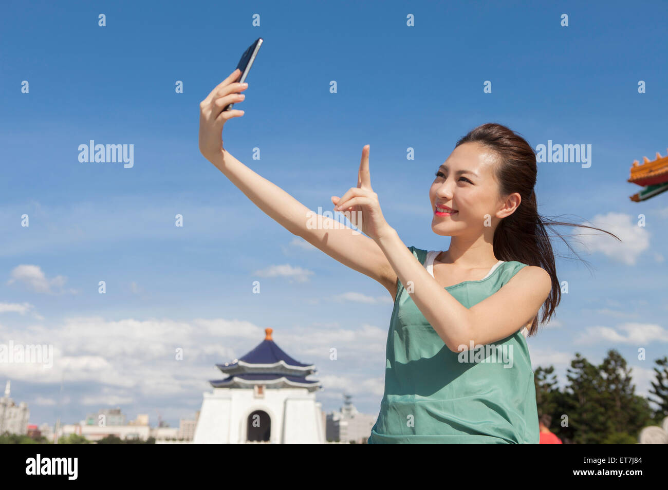 Jeune femme prenant des photos avec smart phone and smiling Banque D'Images