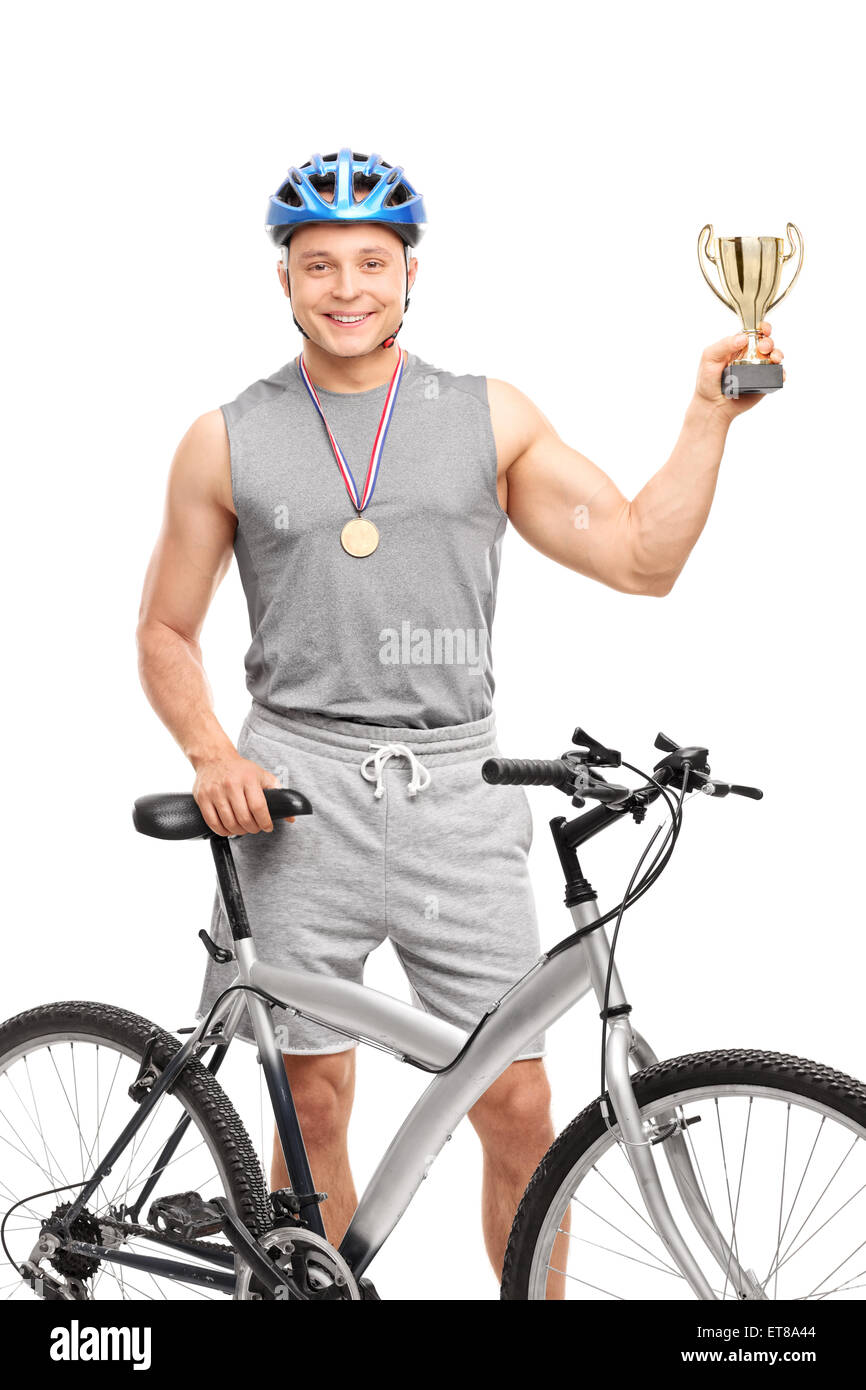 Shot vertical d'un jeune homme biker avec une médaille et un trophée debout derrière un vélo et regardant la caméra Banque D'Images