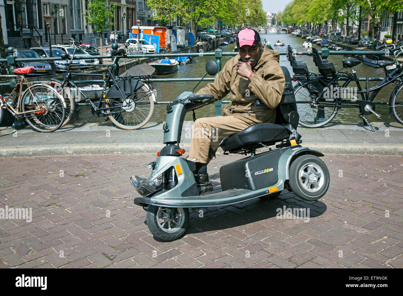 Homme handicapé cascades sur scoot mobile sur Bridge dans le centre d'amsterdam, capitale des Pays-Bas Banque D'Images