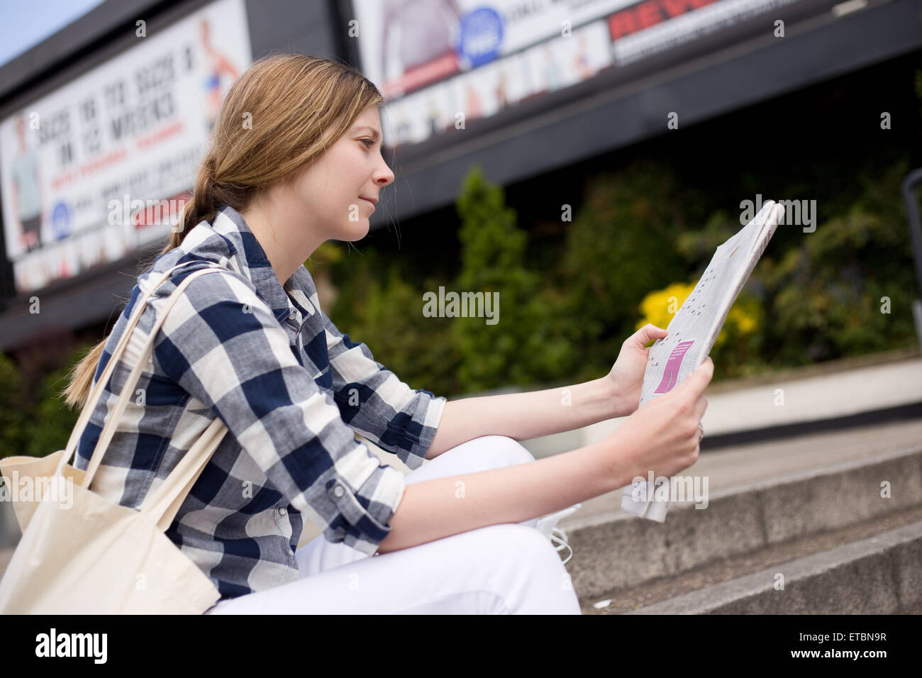 Young woman reading newspaper Banque D'Images