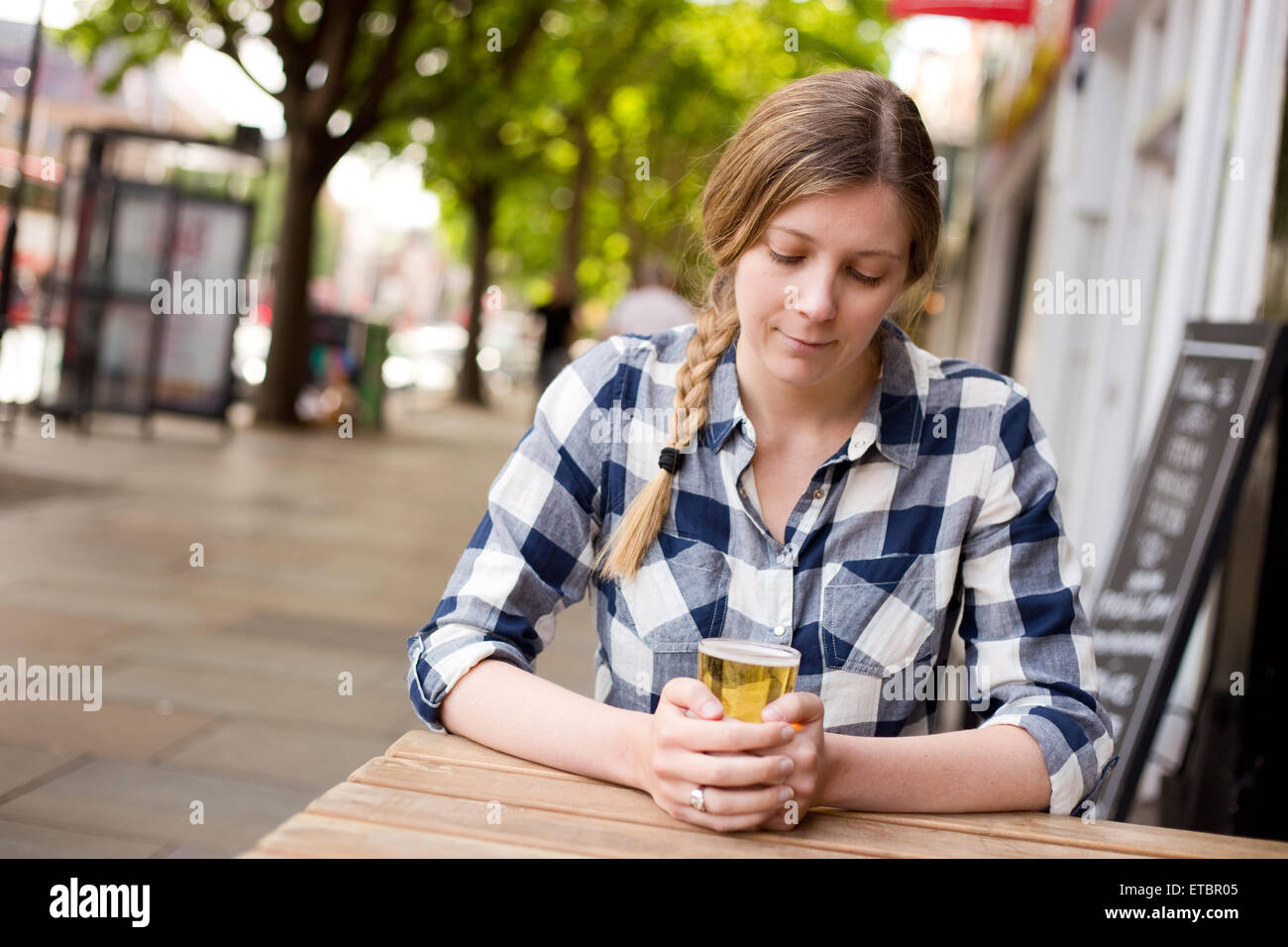 Jeune femme à la bière sa holding réfléchie Banque D'Images