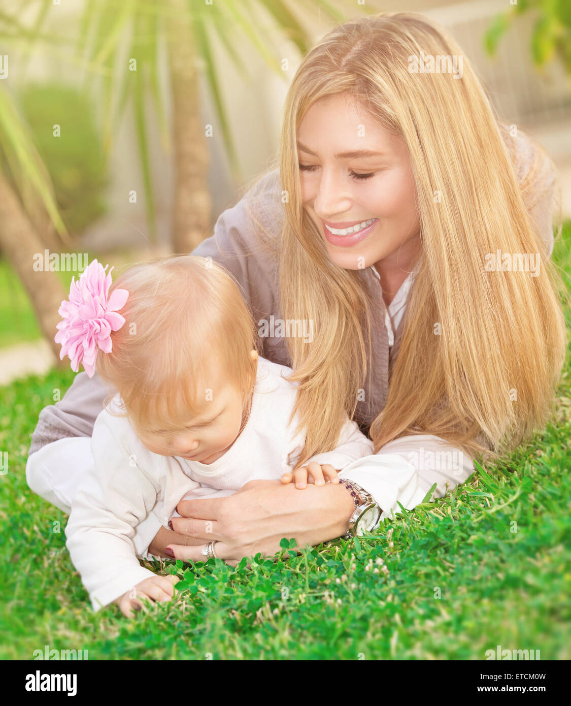 Cheerful young mère jouant avec son adorable petite fille dans le parc, allongé sur l'herbe verte fraîche, champ famille heureuse Banque D'Images
