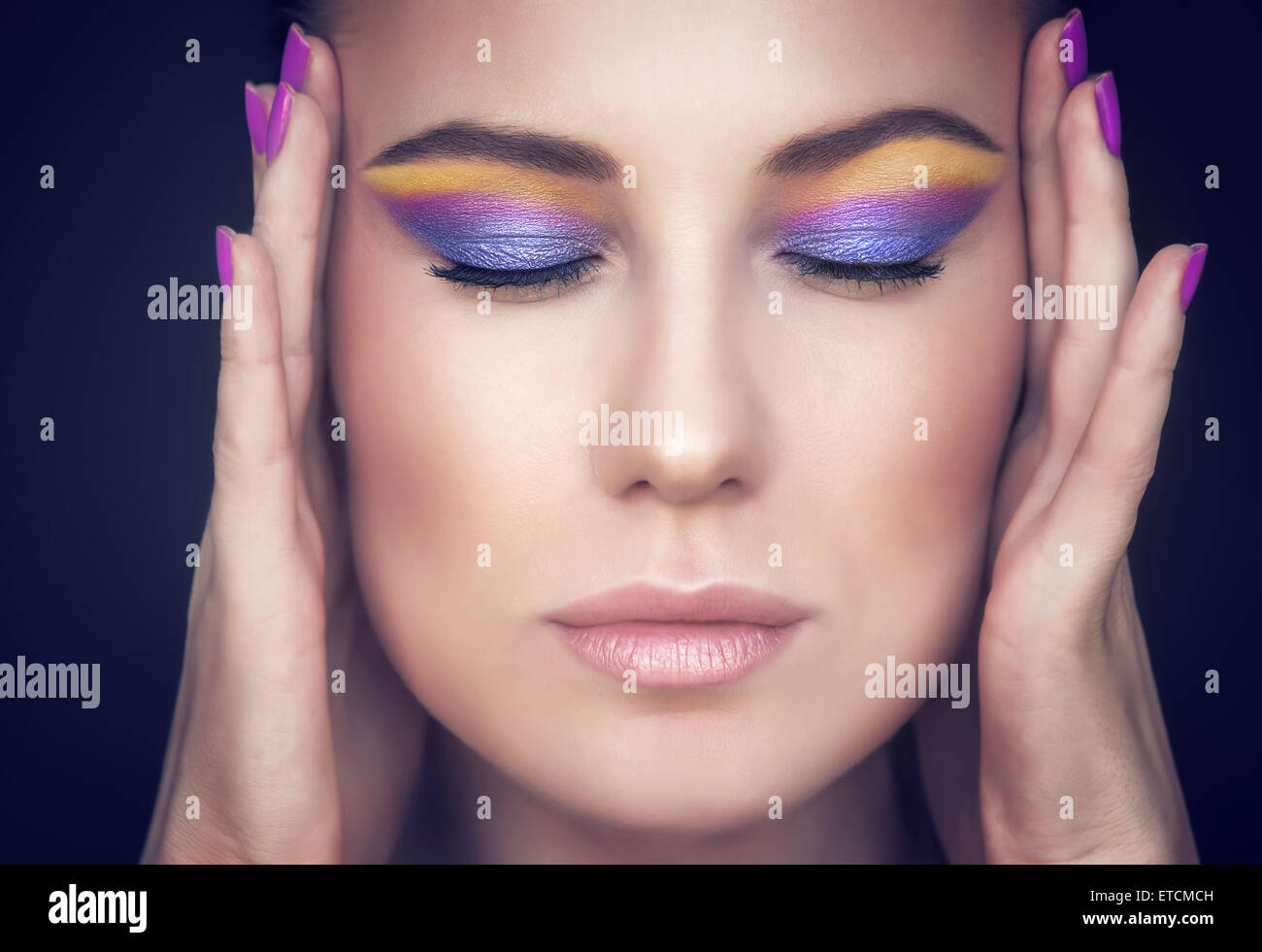 Closeup portrait of a Beautiful woman face aux couleurs de maquillage élégant sur fond sombre, modèle avec les yeux fermés Banque D'Images