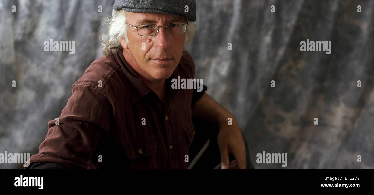 Un vieux homme aux yeux bleus avec des lunettes et des cheveux blancs  portant un t-shirt brun tacheté contre fond gris Photo Stock - Alamy