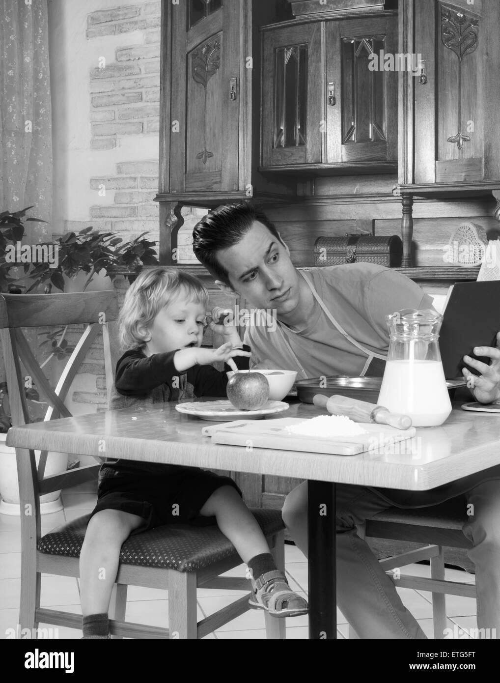 Homme avec petit garçon dans la cuisine préparer un repas. retro Banque D'Images