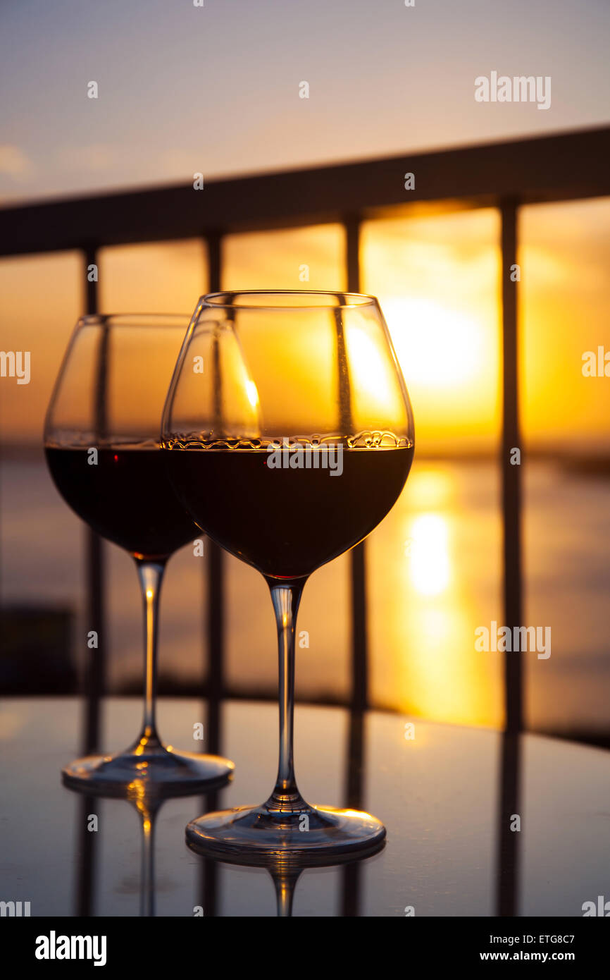 Deux verres de vin rouge en face du soleil couchant. Balcon avec vue sur la mer des Caraïbes contexte Banque D'Images