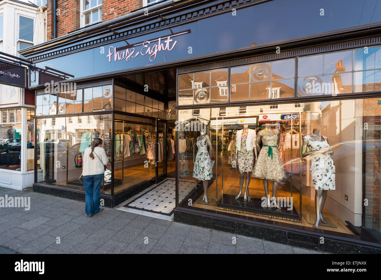 Une femme regarde dans la fenêtre d'affichage d'un magasin de vêtements à Wimborne Minster, Dorset. Le magasin est appelé Phase 8. Banque D'Images