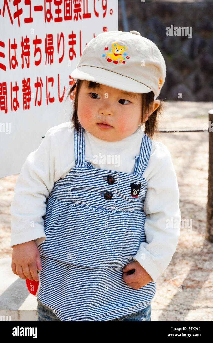 Enfant japonais, fille, 2-3 ans, portant une casquette de baseball, debout  à l'extérieur en se tenant debout par un panneau d'avertissement, regardant  perdu et confus Photo Stock - Alamy
