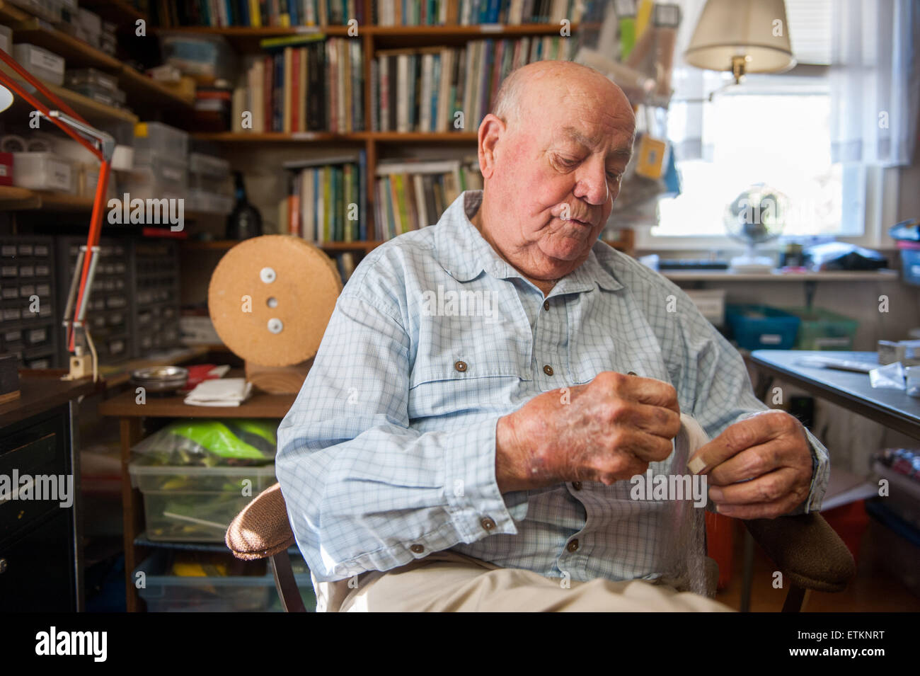 Lefty Kreh, American fly fisherman assis dans son atelier travaille sur un leurre à Linthicum, Maryland, USA Banque D'Images