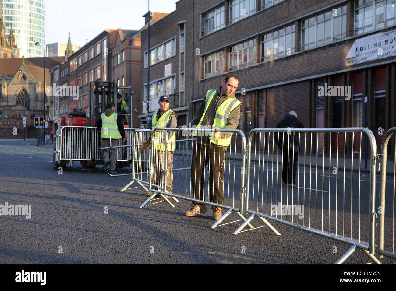 Ouvriers érigeant des barrières pour piétons à l'aube pour le St Patricks Day Parade à Birmingham Banque D'Images
