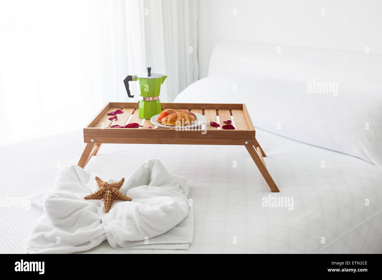 Plateau de bois de petit-déjeuner avec café et croissant sur lit, décoré d'étoiles de mer sur la serviette blanche Banque D'Images Plateau de bois de petit-déjeuner avec café et croissant sur lit, décoré d'étoiles de mer sur la serviette blanche Banque D'Images