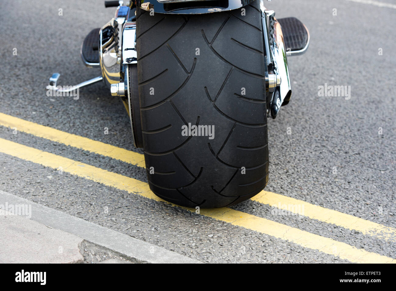 Gros pneu arrière sur une moto Harley Davidson garée sur double lignes  jaunes Photo Stock - Alamy