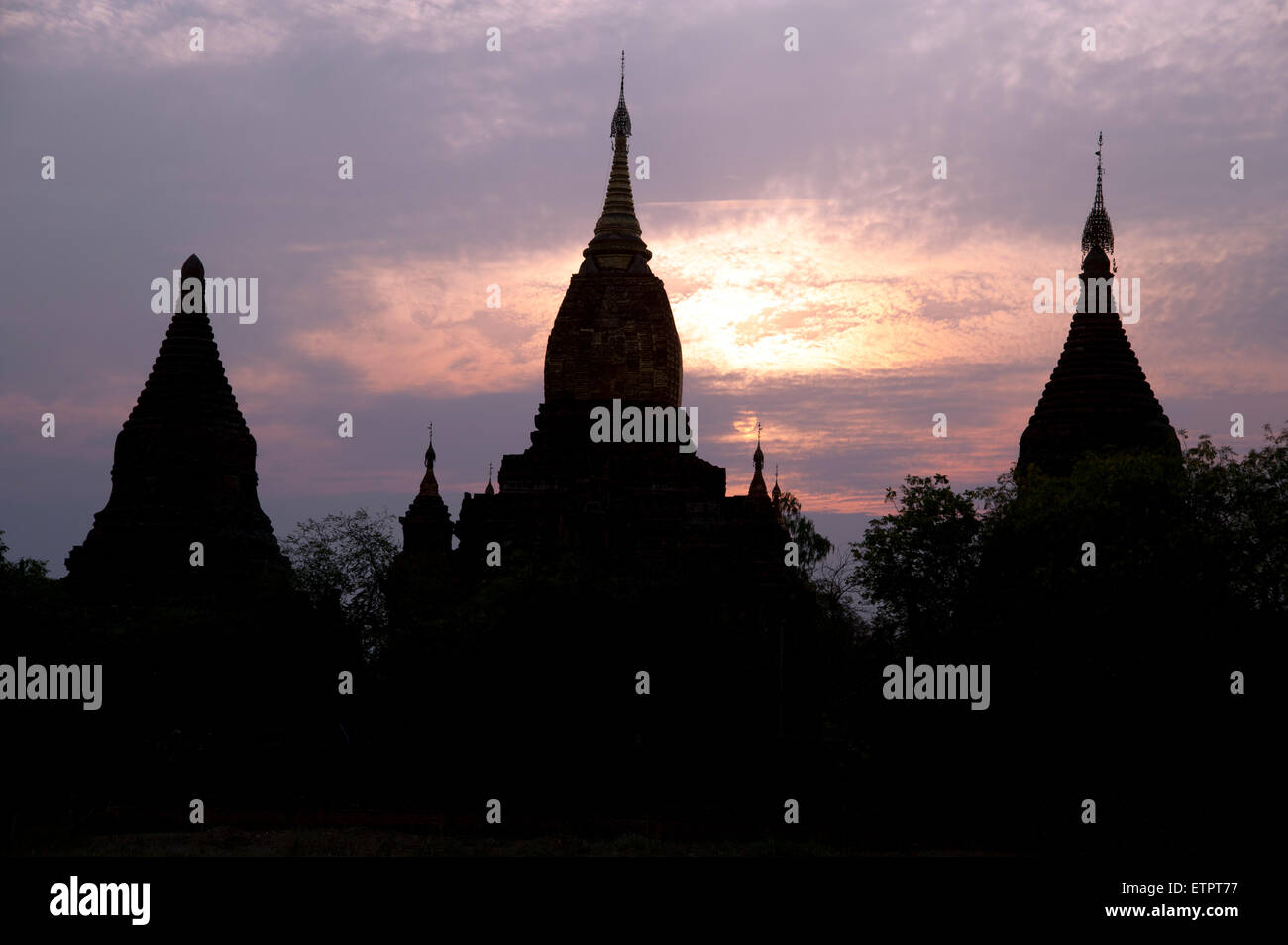 Trois silhouettes sombres des flèches contre le temple d'or d'un coucher de Bagan Myanmar Banque D'Images