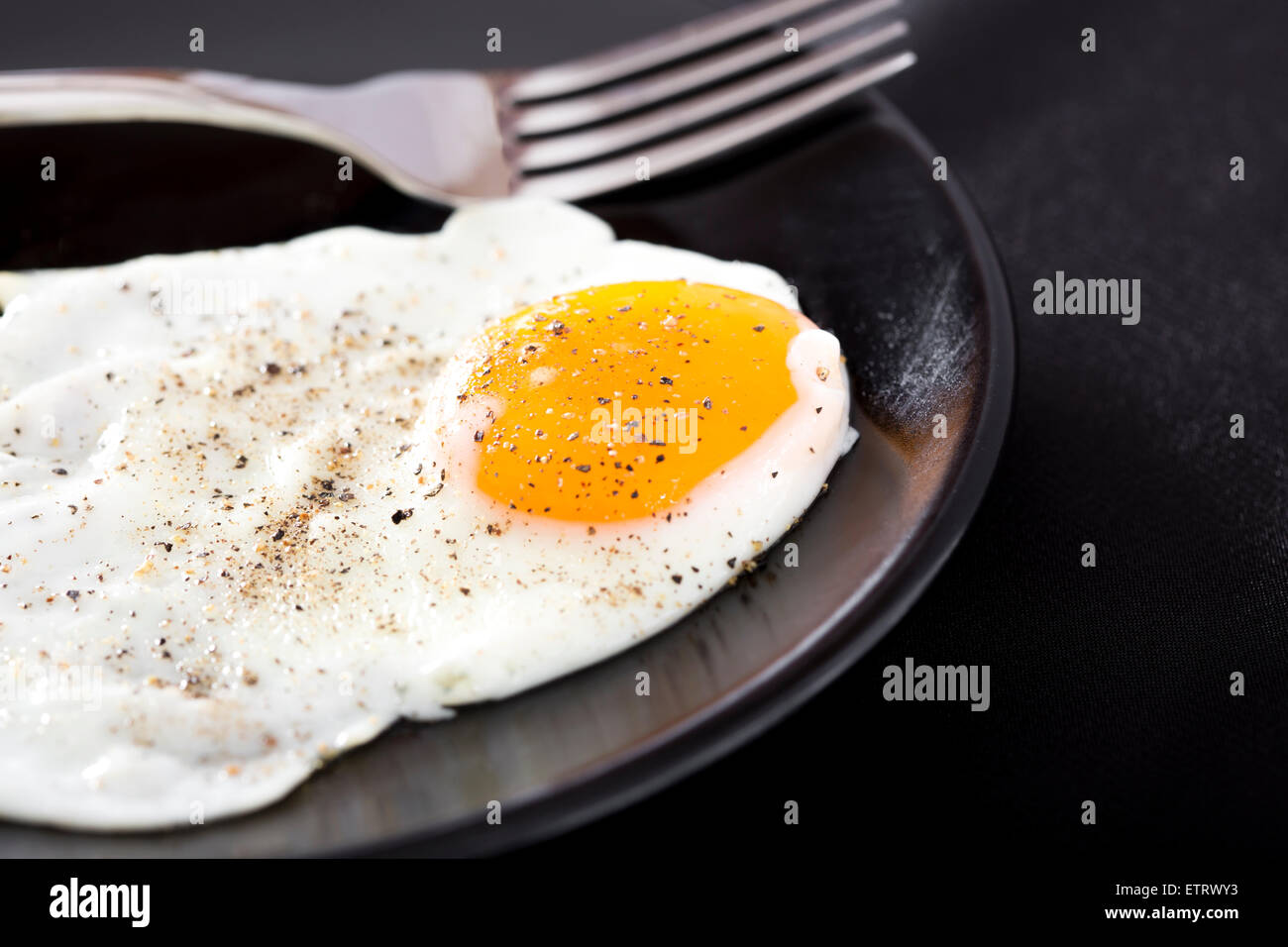 Près d'un œuf frit sur la plaque noire avec silver fork Banque D'Images