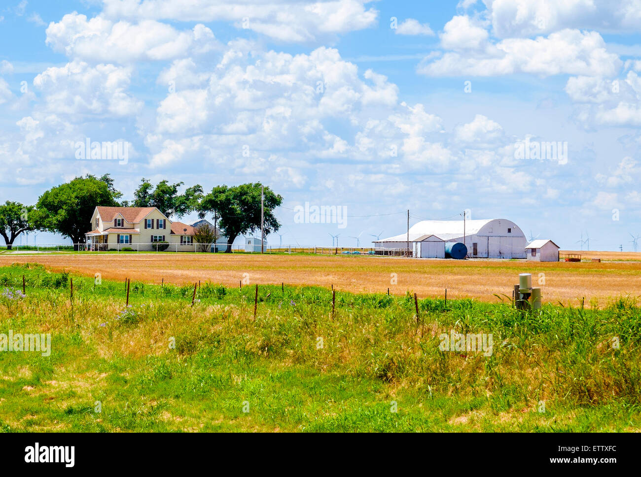 Une ferme avec une maison de deux étages et grange, entouré d'un champ de blé coupé dans les régions rurales de l'Oklahoma, USA. Banque D'Images