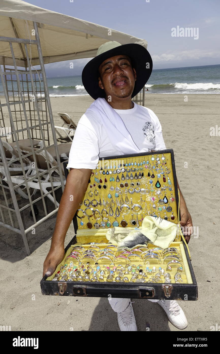 Smiling salesman montrant ses marchandises sur la plage de Puerto Vallarta, Mexique Banque D'Images