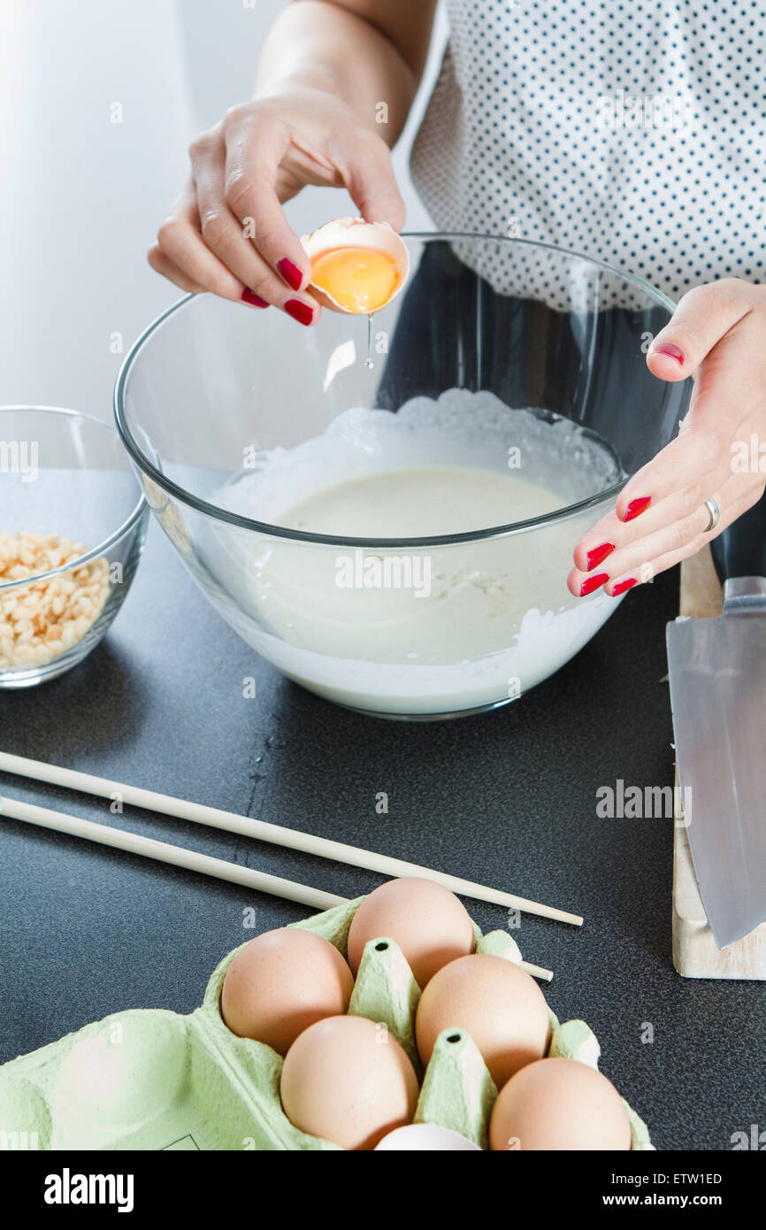 Femme préparant la pâte pour Okonomiyaki dans un glassbowl Banque D'Images