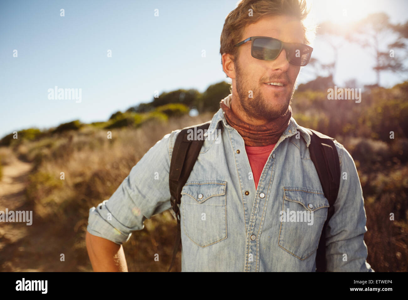 Portrait of happy young man hiking in countryside. Homme de race blanche modèle avec sac à dos en randonnée sur la journée ensoleillée. Vacances d'été en co Banque D'Images