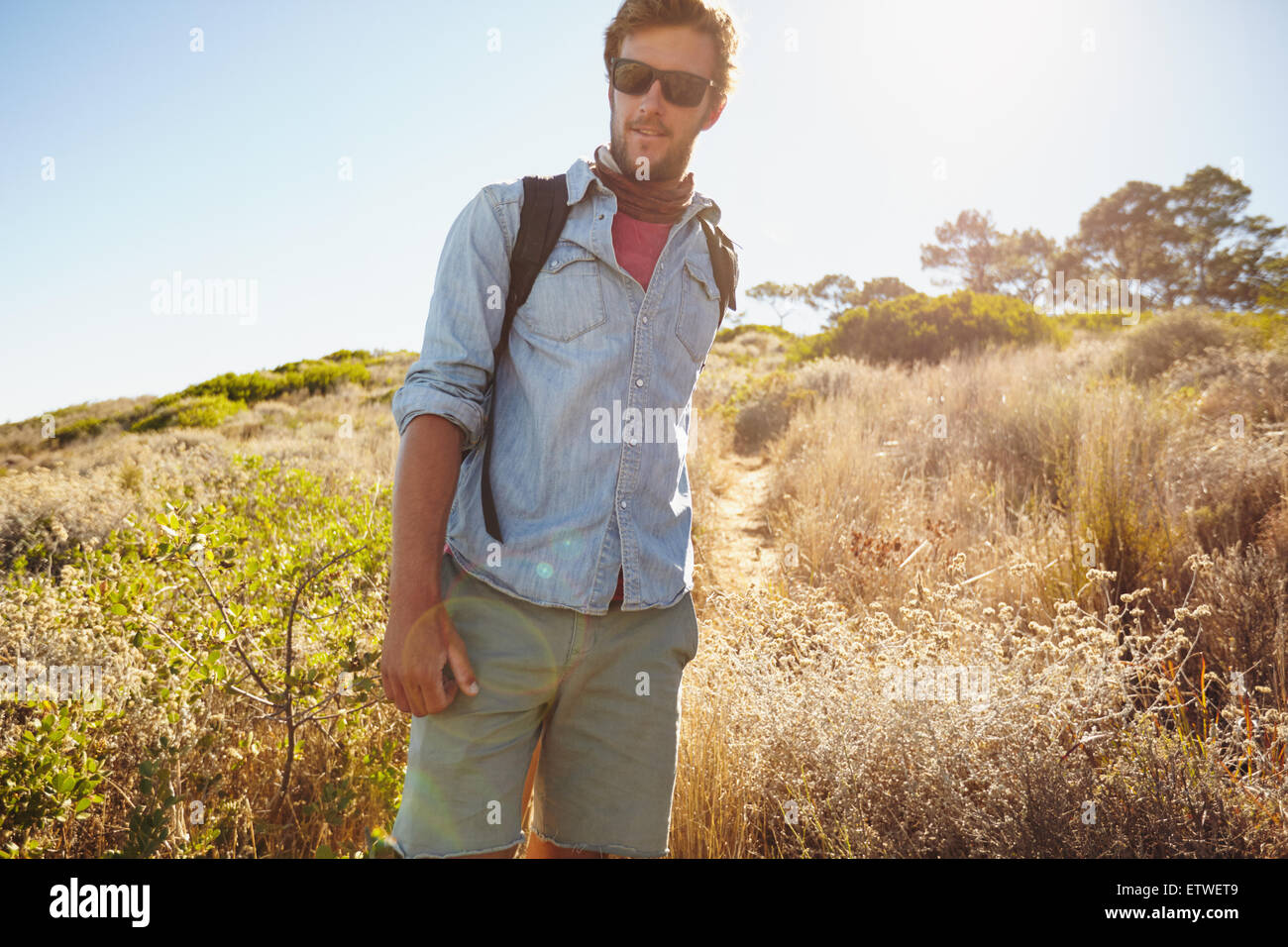 Portrait de beau jeune homme randonnée dans la nature. Caucasian man walking on country trail sur jour ensoleillé chaud. Banque D'Images