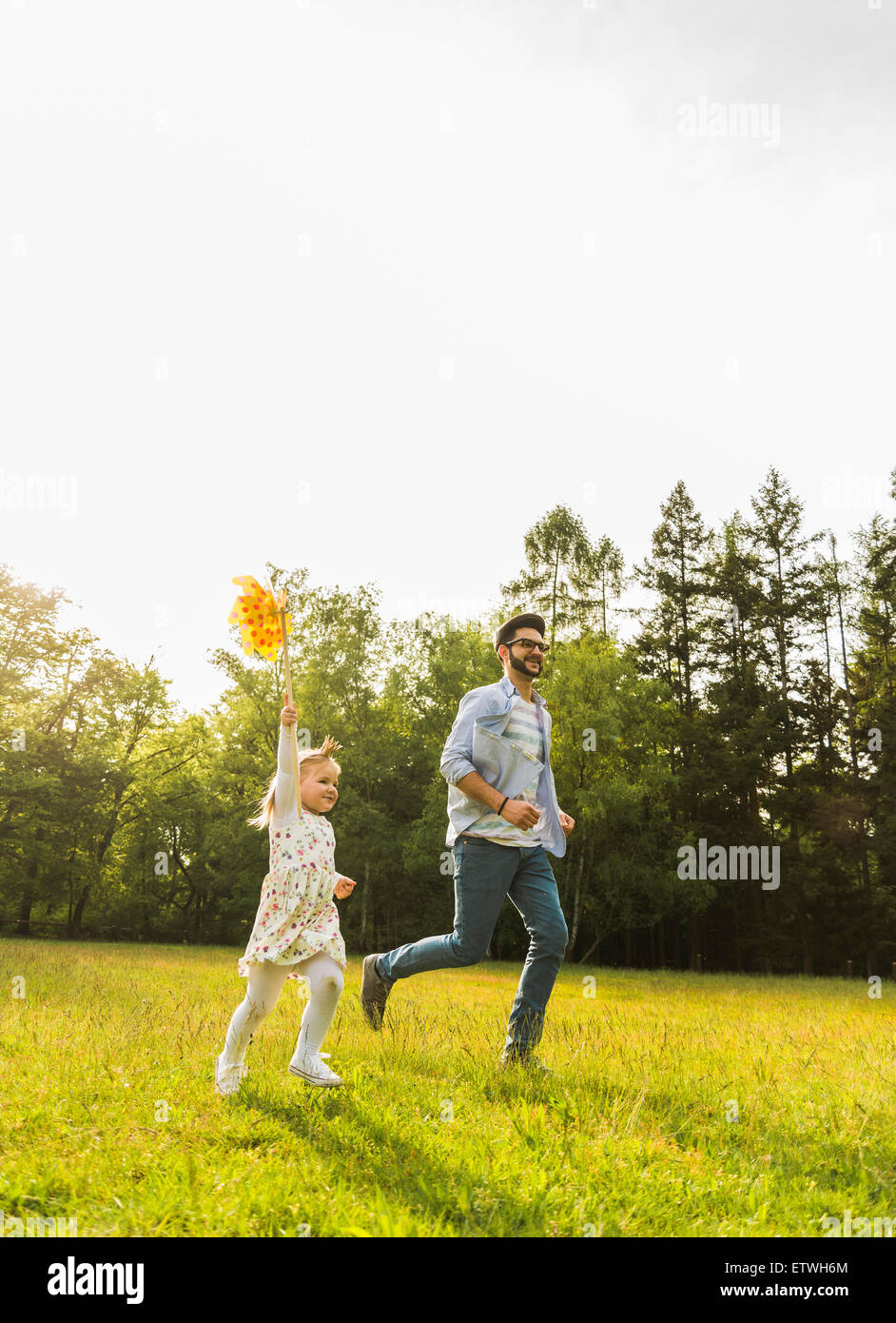 Père et fille exécutant avec papier moulin on meadow Banque D'Images