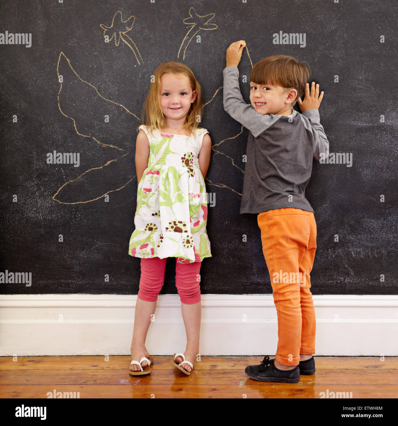 Full Length portrait of cute little girl et little boy drawing angel ailes autour d'elle sur tableau noir. Deux petits enfants p Banque D'Images