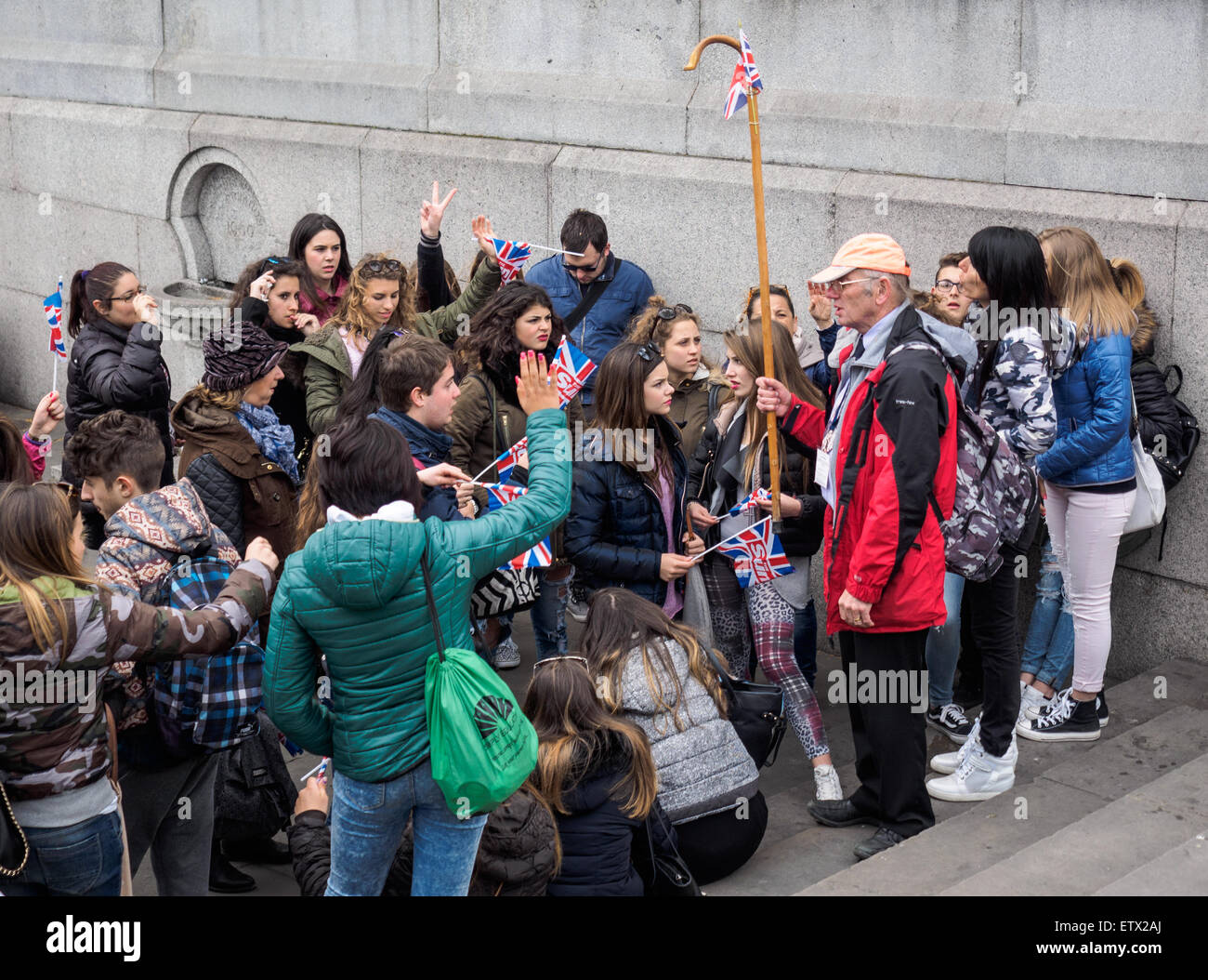 Trafalgar Square Londres. Personnes âgées guide touristique avec groupe de jeunes touristes. Banque D'Images