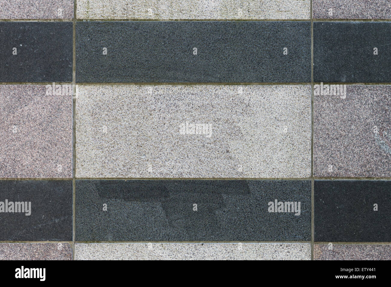 Un mur de pierre gris texturé avec des bandes noires Banque D'Images