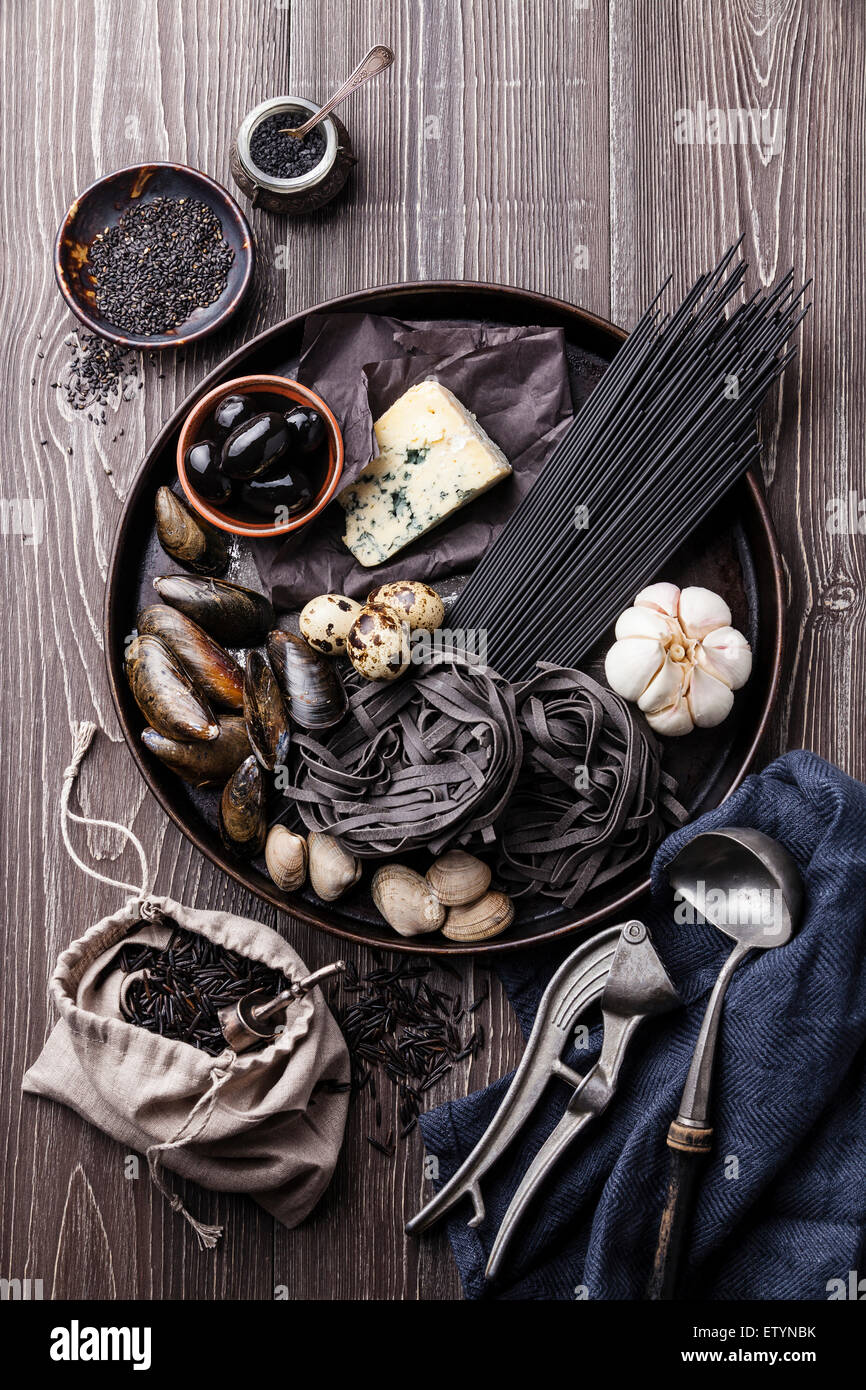 Matières noir Ingrédients alimentaires - Pâtes, olives, les palourdes sur fond de bois Banque D'Images