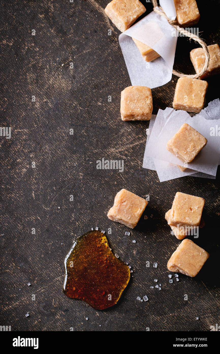 Bonbons au caramel Fudge et sur du papier sulfurisé, servi avec fil sur fond sombre. Vue d'en haut Banque D'Images